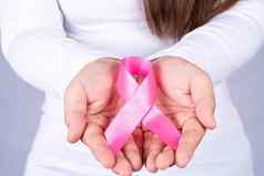 女人手持有粉红色的乳房癌症意识丝带医疗医疗保健广告概念