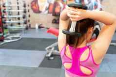 年轻的运动女人肱三头肌扩展哑铃健身房饮食生活方式重量损失获得肌肉健康的锻炼概念