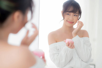 美丽的肖像年轻的亚洲女人应用奶油保湿霜