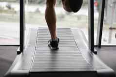 认不出来男人。运行跑步机健身房运动员慢跑室内重量损失锻炼慢跑者运行灰色的墙背景有氧运动培训