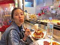年轻的女人吃脆脆的朝鲜文炸鸡街食物