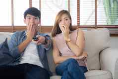 年轻的亚洲夫妇看恐怖电影放松享受