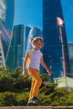 女孩黄色的牛仔裤站背景摩天大楼