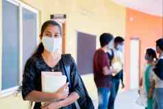 年轻的女孩医疗面具背包书站自信地相机学生背景概念大学reopn安全措施由于冠状病毒科维德