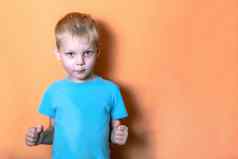 一年男孩蓝色的衬衫粉红色的背景相机镜头紧握的拳头