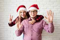快乐圣诞节夫妇圣诞老人帽子白色砖墙背景