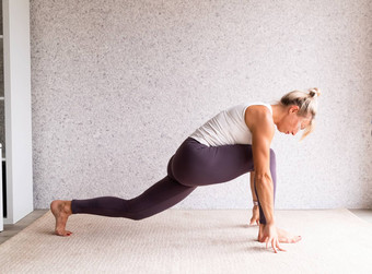 年轻的有吸引力的女人练习瑜伽穿运动服装白色衬衫紫色的裤子室内完整的长度灰色的背景