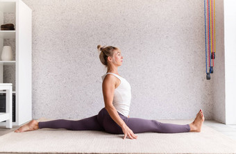 年轻的有吸引力的女人练习<strong>瑜伽</strong>穿运动服装白色衬衫<strong>紫色</strong>的裤子室内完整的长度灰色的背景