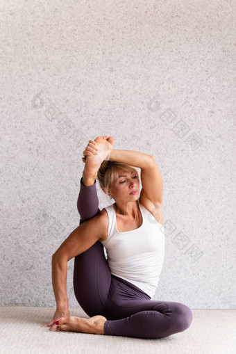 年轻的有吸引力的女人练习<strong>瑜伽</strong>穿运动服装白色衬衫<strong>紫色</strong>的裤子室内完整的长度灰色的背景