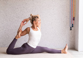 年轻的有吸引力的女人练习<strong>瑜伽</strong>穿运动服装白色衬衫<strong>紫色</strong>的裤子室内完整的长度灰色的背景