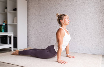 年轻的有吸引力的女人练习瑜伽穿运动服装白色衬衫紫色的裤子室内完整的长度灰色的背景