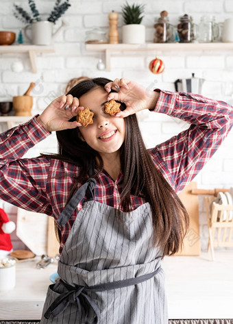 快乐女人围裙持有明星形状的饼干前面眼睛首页厨房背景