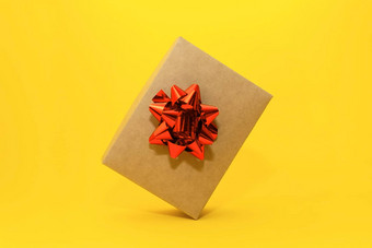 特写镜头工艺礼物盒子红色的弓平衡角落里黄色的背景复制空间现代假期规划