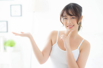 美丽的年轻的亚洲女人微笑显示皮肤护理名单的