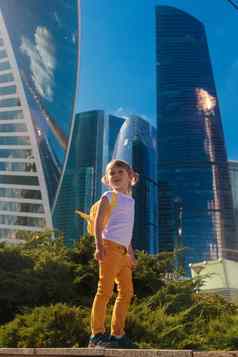 女孩黄色的牛仔裤站背景摩天大楼