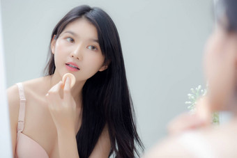 特写镜头手年轻的亚洲女人持有产品化妆品应用