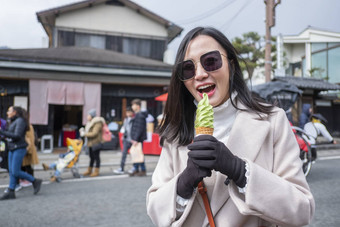 年轻的旅游女人吃冰奶油锥街食物竹子
