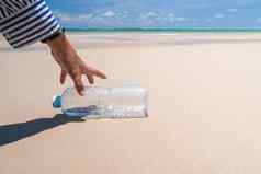 手选择空水瓶垃圾美丽的海滩env