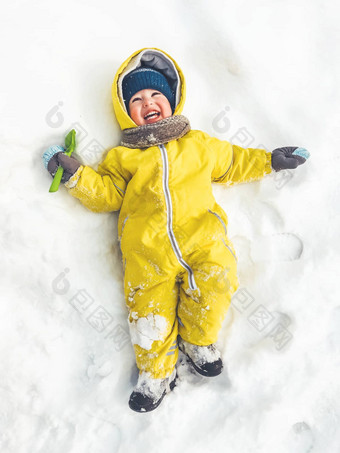 微笑蹒跚学步的明亮的黄色的连身裤说谎雪池