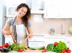 年轻的女人烹饪健康的食物蔬菜沙拉
