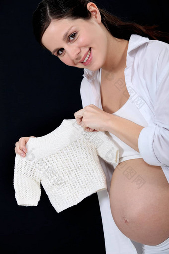 肖像美丽的怀孕了女人持有手工编织套衫