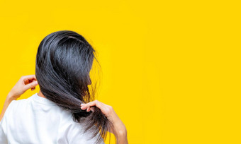 回来视图亚洲女人持有损坏的头发黄色的背景头发损失薄头发问题女人干脆黑色的长头发洗发水护发素水疗中心治疗