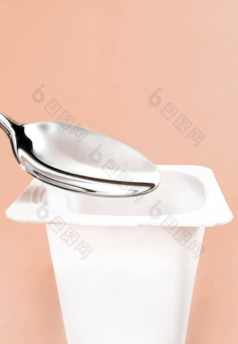 酸奶杯银勺子米色背景白色塑料容器酸奶奶油新鲜的乳制品产品健康的饮食营养平衡