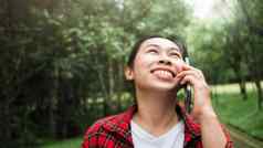 快乐的女旅游会谈智能手机微笑脸放松自然公园概念技术幸福