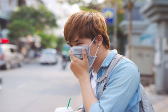 亚洲男人。街穿保护面具生病的男人。流感穿面具吹鼻子餐巾疫情流感概念街