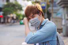 亚洲男人。街穿保护面具生病的男人。流感穿面具吹鼻子餐巾疫情流感概念街