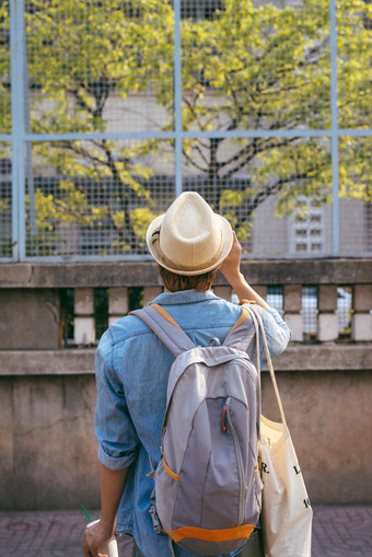 享受旅行年轻的微笑男人。背包持有相机亚洲街