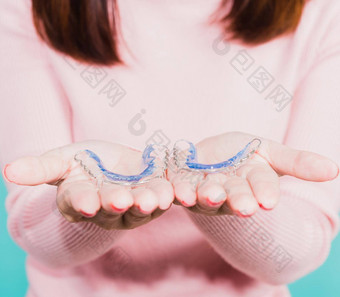 关闭手年轻的女人持有硅胶矫正家臣牙齿