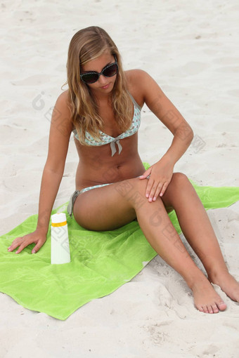 年轻的女人应用防晒霜海滩