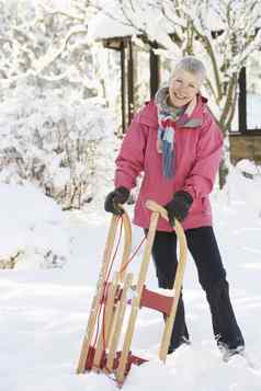 高级女人持有雪橇雪景观