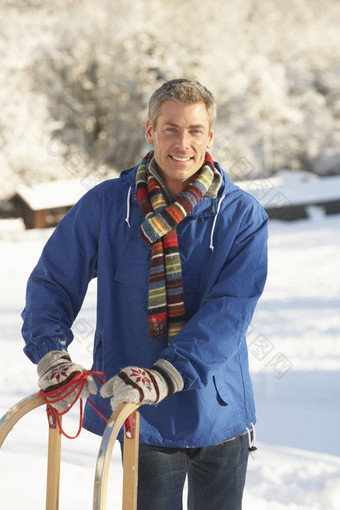 中间岁的男人。站雪景观持有雪橇
