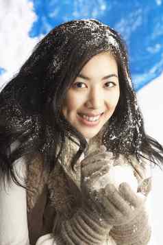 年轻的女人穿温暖的冬天衣服持有雪球螺柱