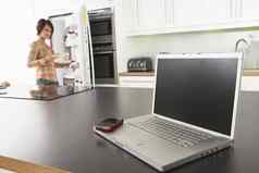 年轻的女人修复零食厨房移动PC现代厨房