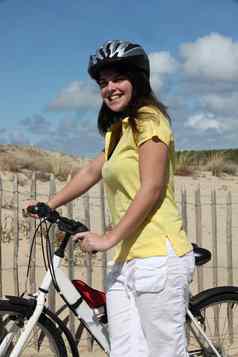 女人采取自行车骑海滩