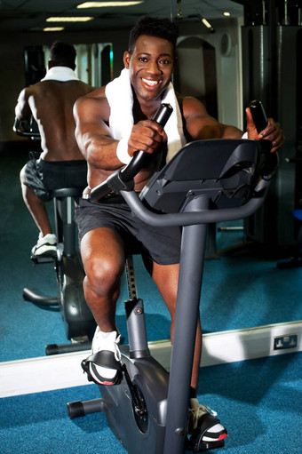 肌肉发达的男人。练习自行车健身房