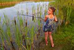 漂亮的年轻的女孩钓鱼河夏天