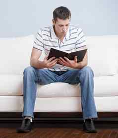 年轻的男人。坐着沙发阅读