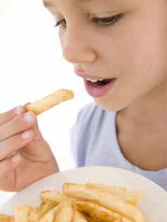 年轻的女孩吃法国薯条