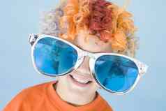 年轻的男孩穿小丑假发太阳镜微笑