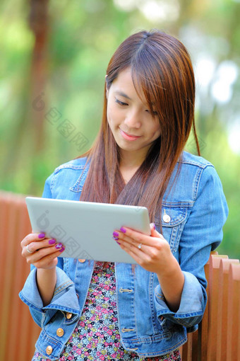 年轻的亚洲女人平板电脑电脑户外