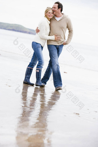 夫妇走海滩手臂手臂微笑