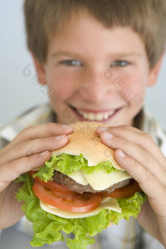 年轻的男孩吃芝士<strong>汉堡</strong>微笑