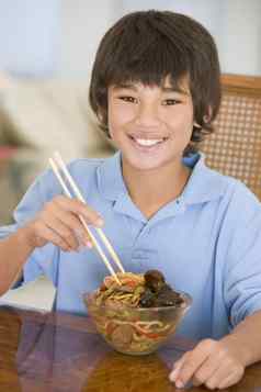 年轻的男孩餐厅房间吃中国人食物微笑