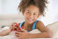 年轻的女孩吃草莓生活房间微笑
