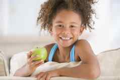 年轻的女孩吃苹果生活房间微笑