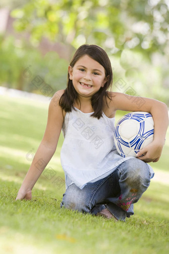年轻的女孩在户外公园持有球微笑